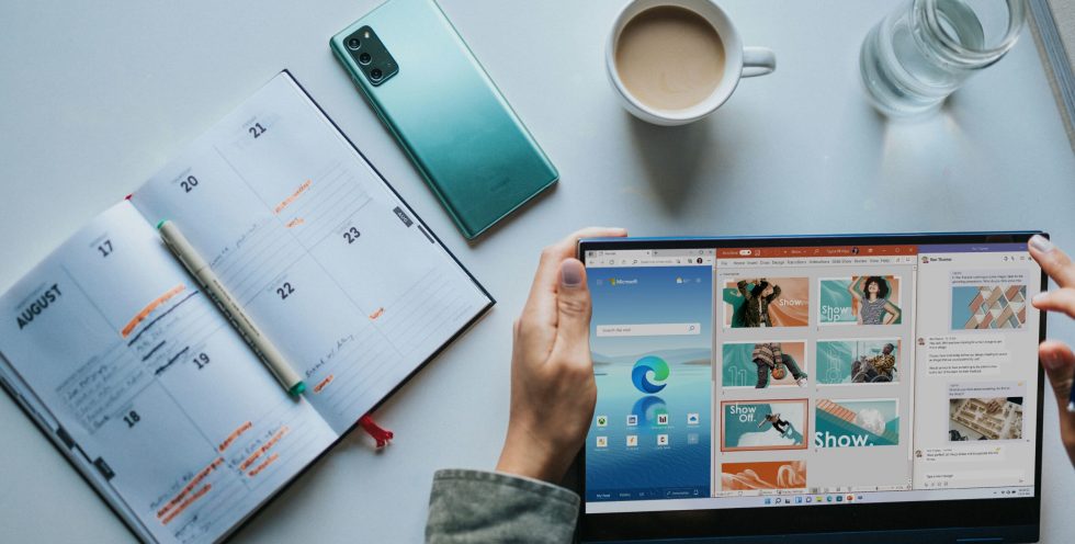 person using Windows 11 computer beside white ceramic mug on white table