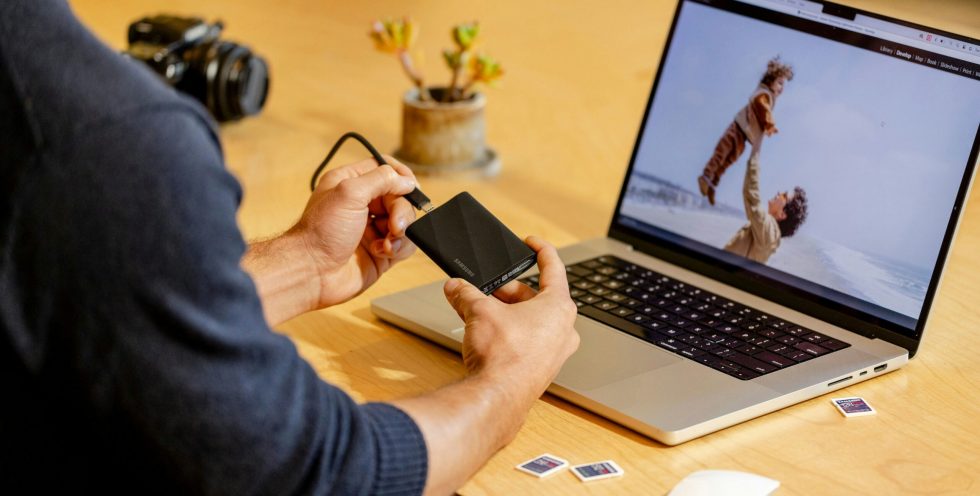 A man sitting at a table with a laptop and cell phone