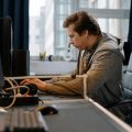 Free A concentrated professional working at a computer in a modern office setting. Stock Photo